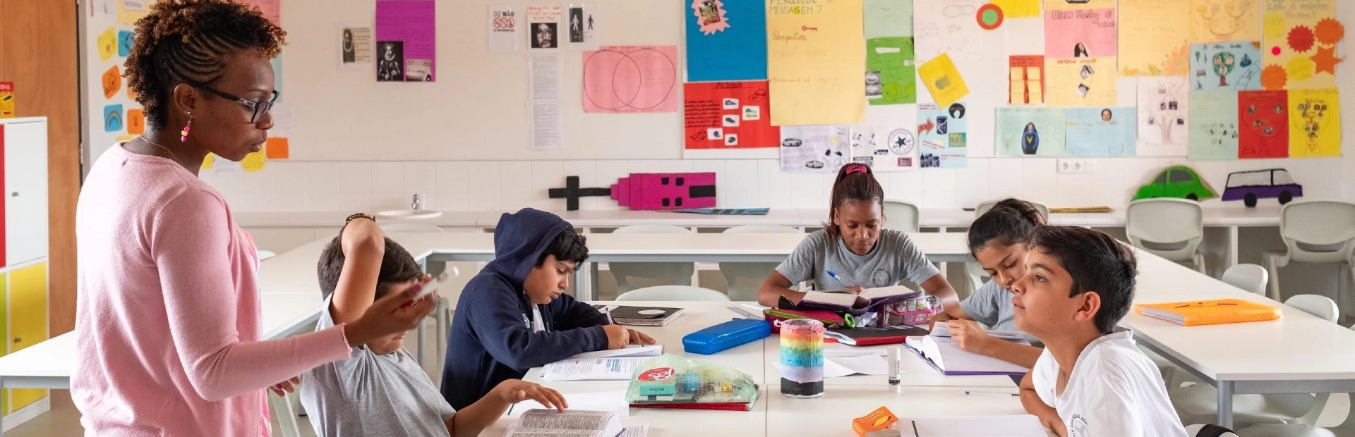 Students working on an assignment in a classroom with their teacher.